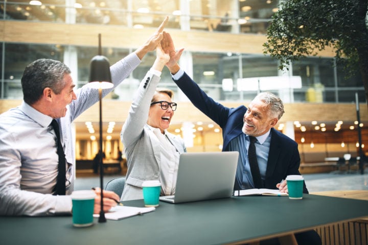 Ecstatic Businesspeople High Fiving Each Other In An Office